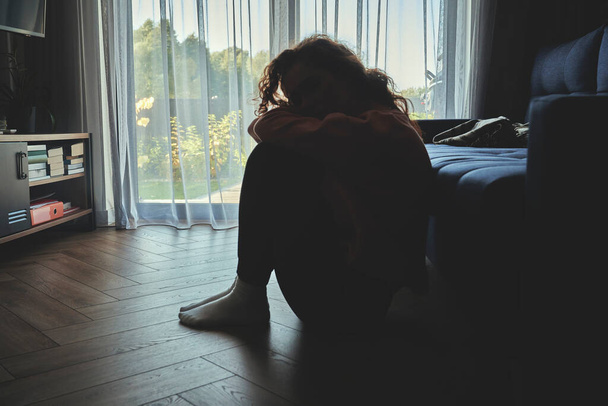 Depresso giovane donna caucasica pavimentazione in silenzio in camera oscura - Foto, immagini