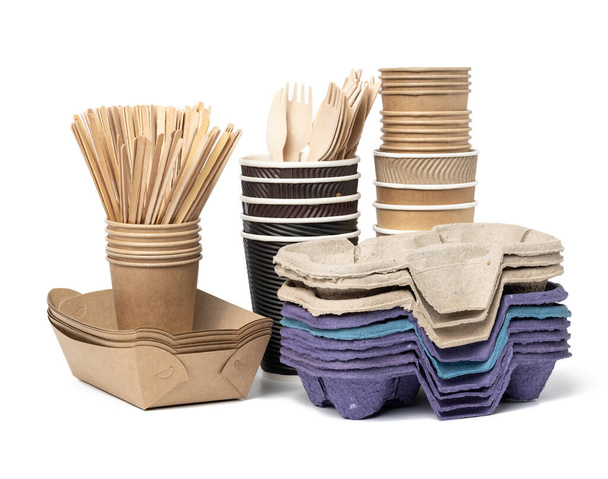 stack of brown disposable paper cups, wooden forks and knives, plate on a white background. Utensils for takeaway drinks, zero waste - Photo, Image