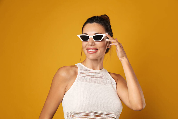 Beautiful woman in sunglasses on yellow background - Фото, зображення