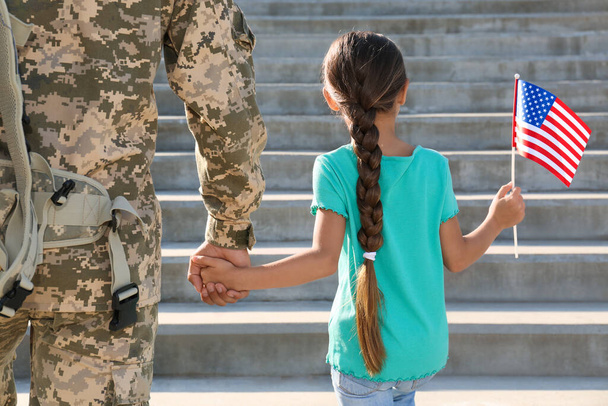 Soldaat en zijn dochtertje met Amerikaanse vlag buiten, achteraanzicht. Veteranendag in de VS - Foto, afbeelding
