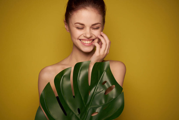 beautiful woman clean skin palm leaf cosmetics yellow background - Fotó, kép
