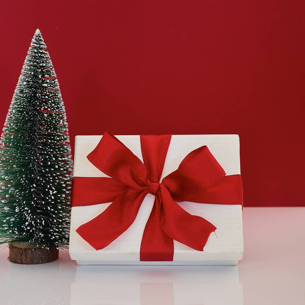 Composition with Christmas gift box with Christmas tree decoration on red background - Photo, Image