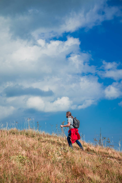 randonnée en montagne et tourisme style de vie portrait masculin d'une personne qui va sur la crête supérieure des hautes terres avec un ciel bleu foncé nuageux dramatique arrière-plan, photographie verticale - Photo, image