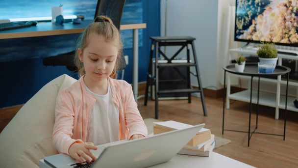 Pieni lapsi, joka käyttää näppäimistöä kannettavalla tietokoneella kotitehtäviin ja verkkokursseihin - Valokuva, kuva