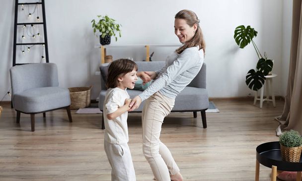 Забавный дошкольник дурачится с матерью, держащейся за руки и танцующей вместе. - Фото, изображение