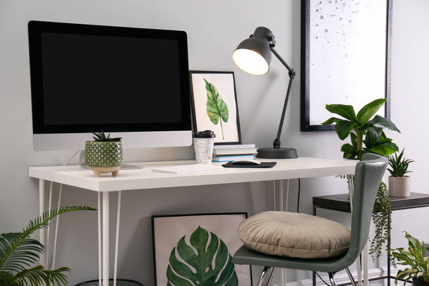 Comfortable workplace with modern computer and houseplants in room. Interior design - Photo, image