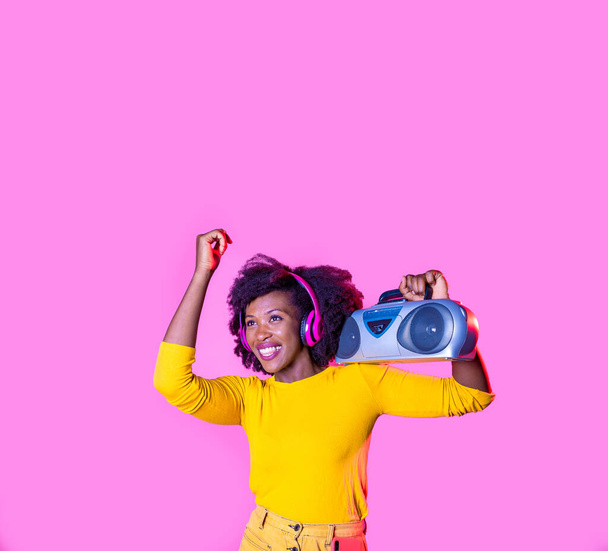 若い黒人女性ダンスリスニング音楽を保持boombox無線ヘッドフォン笑顔幸せな孤立した広告コピースペースの背景 - 写真・画像