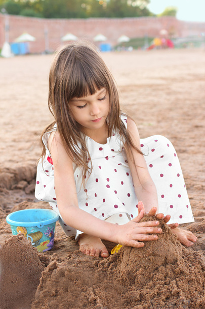 Cute little girl making sand castle on river beach. Femininity concept - Foto, immagini
