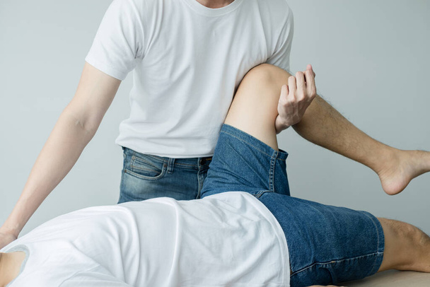 男性患者は診察と治療のために膝痛の問題を理学療法士に相談した。リハビリテーション理学療法の概念. - 写真・画像