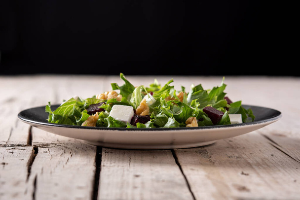 Beetroot salad with feta cheese,lettuce and walnuts on rustic wooden table - Foto, afbeelding