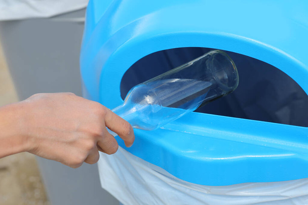 mano del joven que arroja una botella de vidrio en la papelera de reciclaje - Foto, imagen
