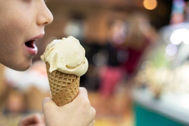 segurar uma deliciosa bola de sorvete de um cone de waffle em suas mãos na rua, horizonta - Foto, Imagem