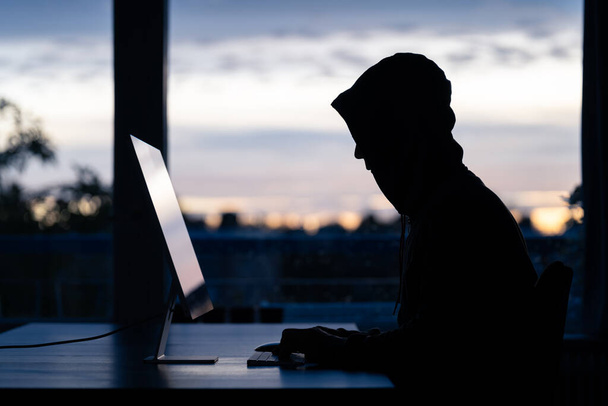 Um hacker cometendo crimes digitais em um computador desktop. - Foto, Imagem
