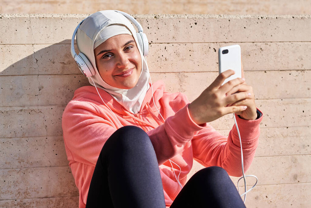 Μουσουλμάνα νεαρή γυναίκα με ακουστικά που κάνει διάλειμμα - Φωτογραφία, εικόνα