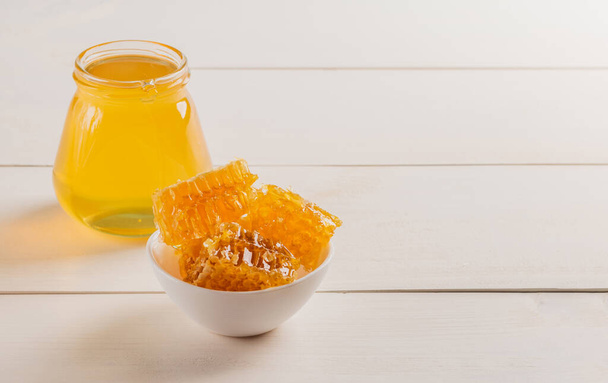 Hřeben v bílém šálku a čerstvý med ve sklenici na dřevěném stole. Kopírovat prostor. - Fotografie, Obrázek