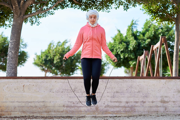 Muslim woman athlete skipping rope outdoors - Фото, зображення