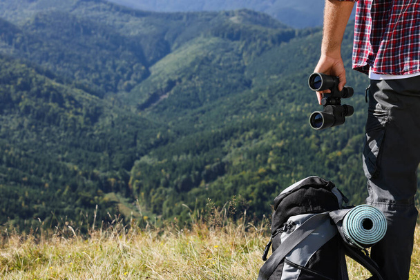 Back view of tourist with hiking equipment and binoculars in mountains, closeup - Fotó, kép