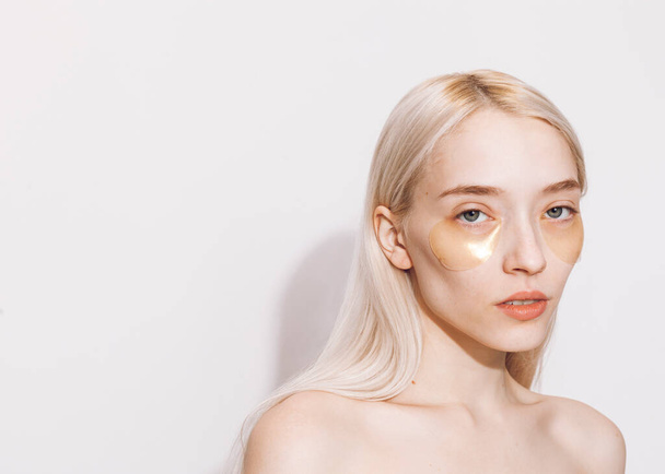 beautiful blonde with gold eye patches on a light background - Zdjęcie, obraz
