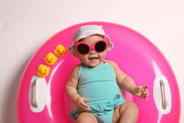 Cute little baby in sunglasses with inflatable ring on white background, top view - Foto, Bild
