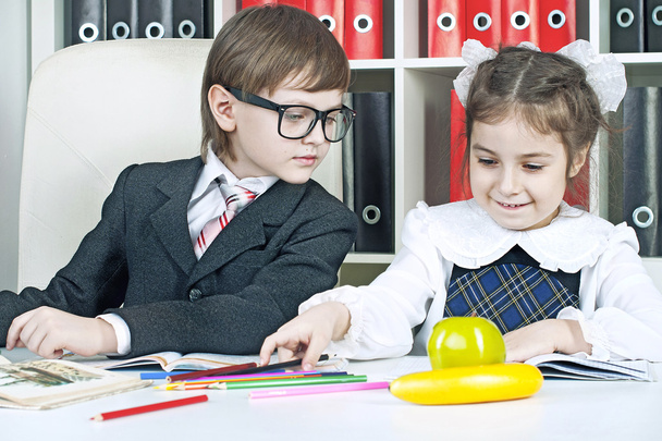 хлопчик і дівчинка сидять за столом у школярів з книгами
 - Фото, зображення