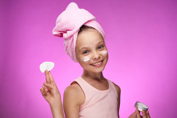 ragazza con un asciugamano sulla sua testa cosmetici decorazione primo piano sfondo viola - Foto, immagini
