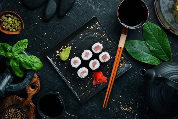 Maki sushi rolls with salmon on a black stone plate. Top view. - 写真・画像
