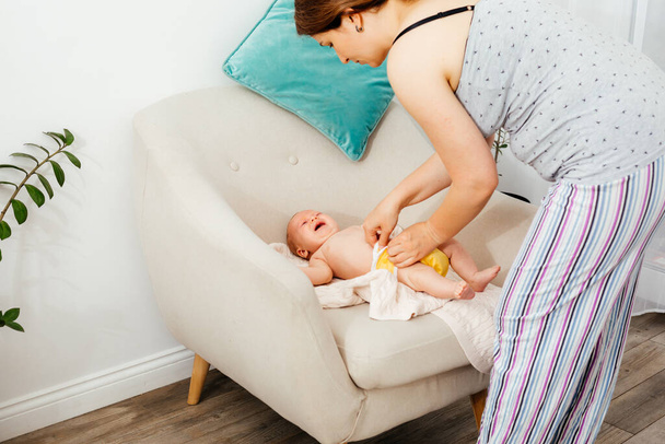 Moeder verschonen herbruikbare luier op haar pasgeboren baby op de stoel - Foto, afbeelding