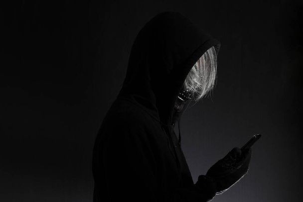 Ο άνθρωπος του τρόμου με τη μάσκα του κρανίου στέκεται στο σκοτάδι. - Φωτογραφία, εικόνα