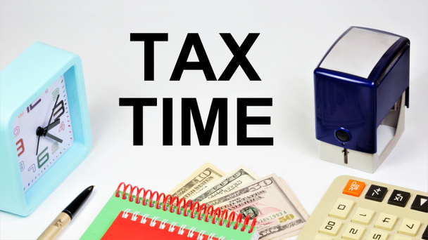 Tax time. An inscription on the background of banknotes, a calculator and hours of reminders about the planning of payment of bills. - Photo, Image