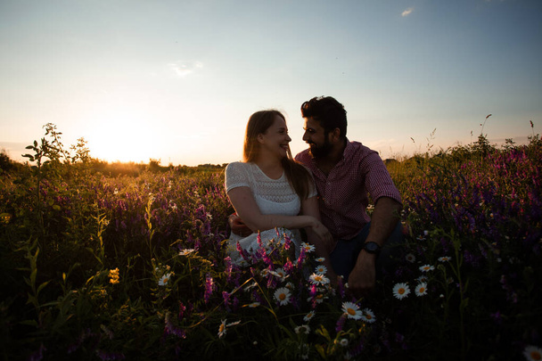 Romantic couple, sitting in the meadow, embracing outdoors - Photo, Image