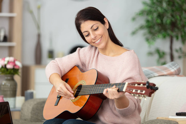 cheerful woman playing a guitar at home - Foto, Imagem
