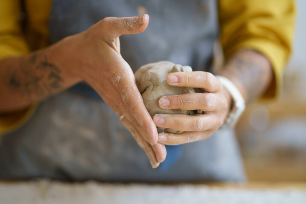 Artista alfarera femenina manos moldeando arcilla cruda. Mujer ceramista en delantal prepararse para dar forma a la cerámica - Foto, Imagen