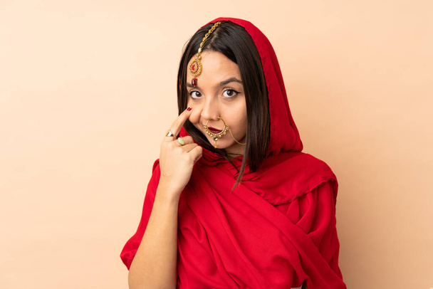 Giovane donna indiana isolata su sfondo beige mostrando qualcosa - Foto, immagini