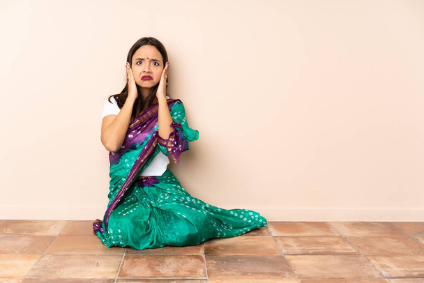Nuori intialainen nainen istuu lattialla turhautunut ja peittää korvat - Valokuva, kuva