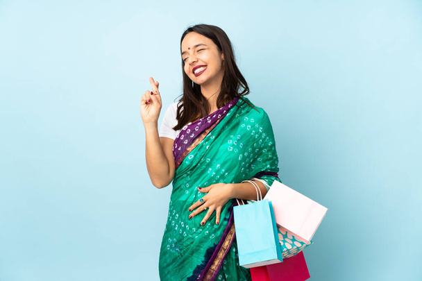 Νεαρή Ινδή γυναίκα με τσάντες ψώνια με τα δάχτυλα σταυρώνουν και εύχονται το καλύτερο - Φωτογραφία, εικόνα