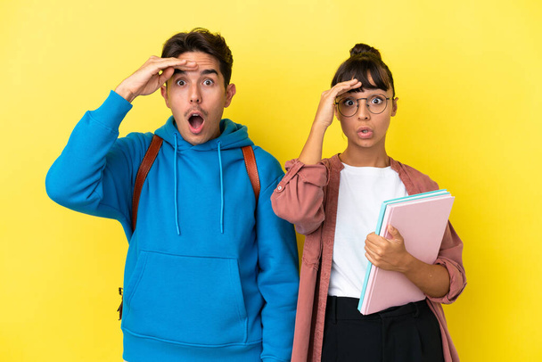 Young student couple isolated on yellow background has just realized something and has intending the solution - Photo, Image