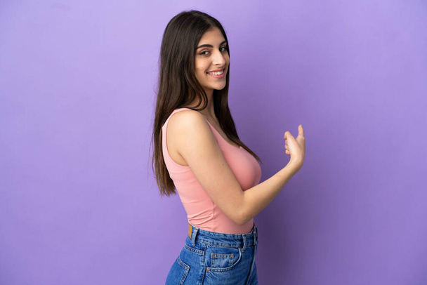 Young caucasian woman isolated on purple background pointing back - Fotografie, Obrázek