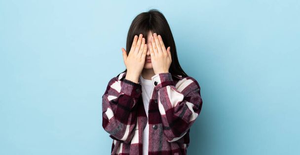 Teenager Ukrainian girl isolated on blue background covering eyes by hands - Фото, зображення