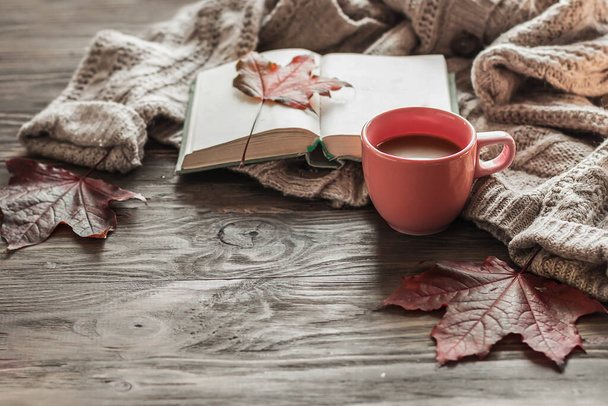 Podzimní ranní káva. Šálek kávy na dřevěném stole a teplý svetr na pozadí podzimního listí. Koncept zátiší. Kopírovat prostor. - Fotografie, Obrázek