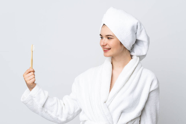 Jovem mulher em um roupão de banho segurando escova de dentes com expressão feliz - Foto, Imagem
