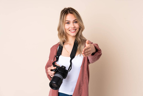 Mladý fotograf dívka přes izolované pozadí třesoucí se ruce pro uzavření dobrý obchod - Fotografie, Obrázek