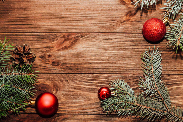 Fondo de Navidad con ramita de abeto y juguetes rojos en tablas de madera. - Foto, Imagen