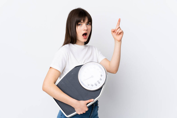 Young Ukrainian woman isolated on white background with weighing machine - 写真・画像