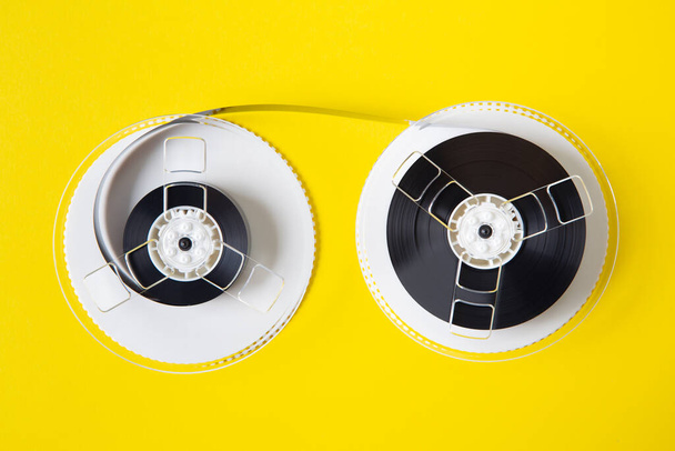 Reel of an old VHS videotape seen up close against a yellow background and meters of magnetic tape around it - 写真・画像