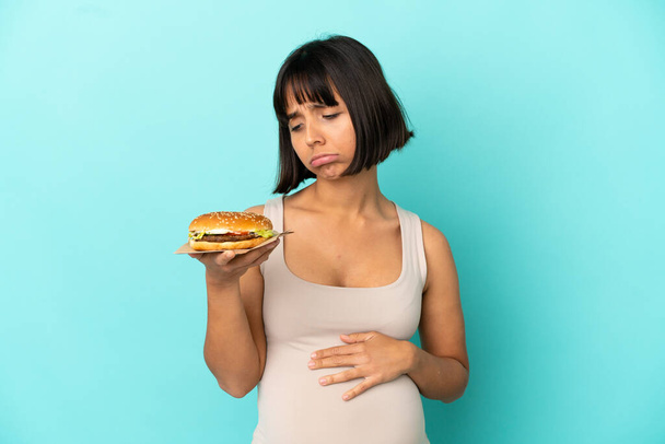 Young pregnant woman holding burge over isolated background - Foto, immagini