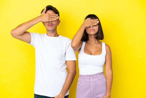 Young mixed race couple isolated on yellow background covering eyes by hands. Do not want to see something - Photo, Image
