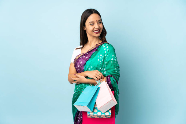 Mujer india joven con bolsas de compras mirando a un lado y sonriendo - Foto, Imagen