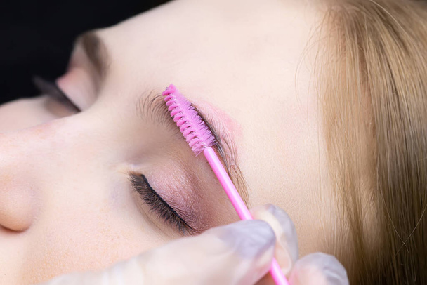 eyebrow lamination the master combs the client's eyebrows with a brush - Fotó, kép