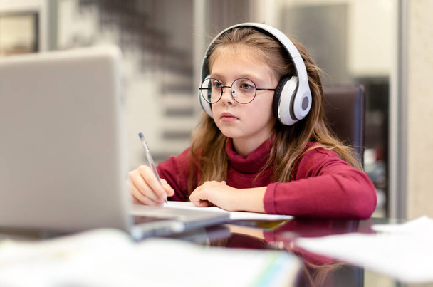 Aranyos kislány komolyan csinál házi feladatot használ laptop otthon az online oktatás, otthoni tanulás és az online kommunikáció. A gyerekek távoktatásban. Társadalmi távolság. Maradj otthon.. - Fotó, kép