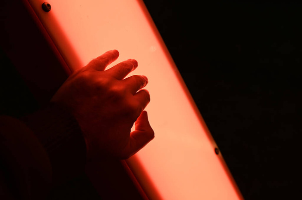 A male's hand touching a led light on a dark background - Fotó, kép
